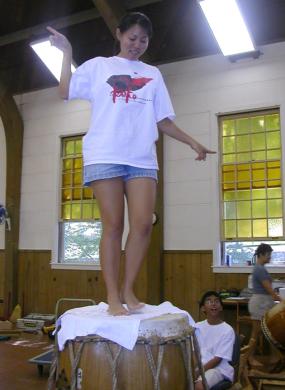Woman standing on top of a drum head to test the tension